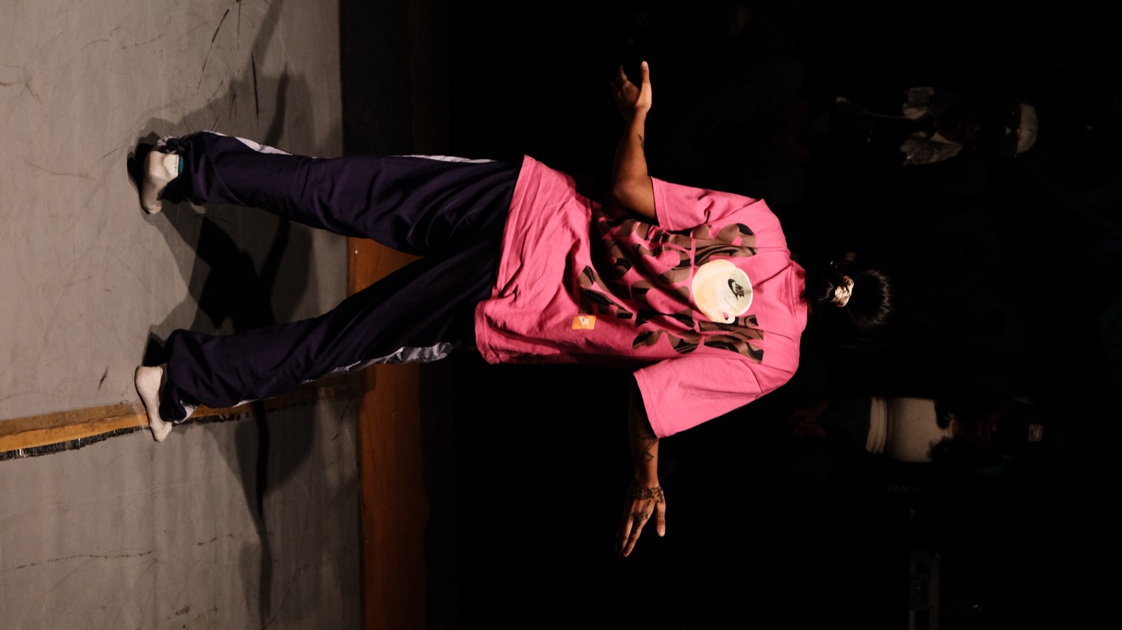 A dancer in pink standing arms wide on the open floor
