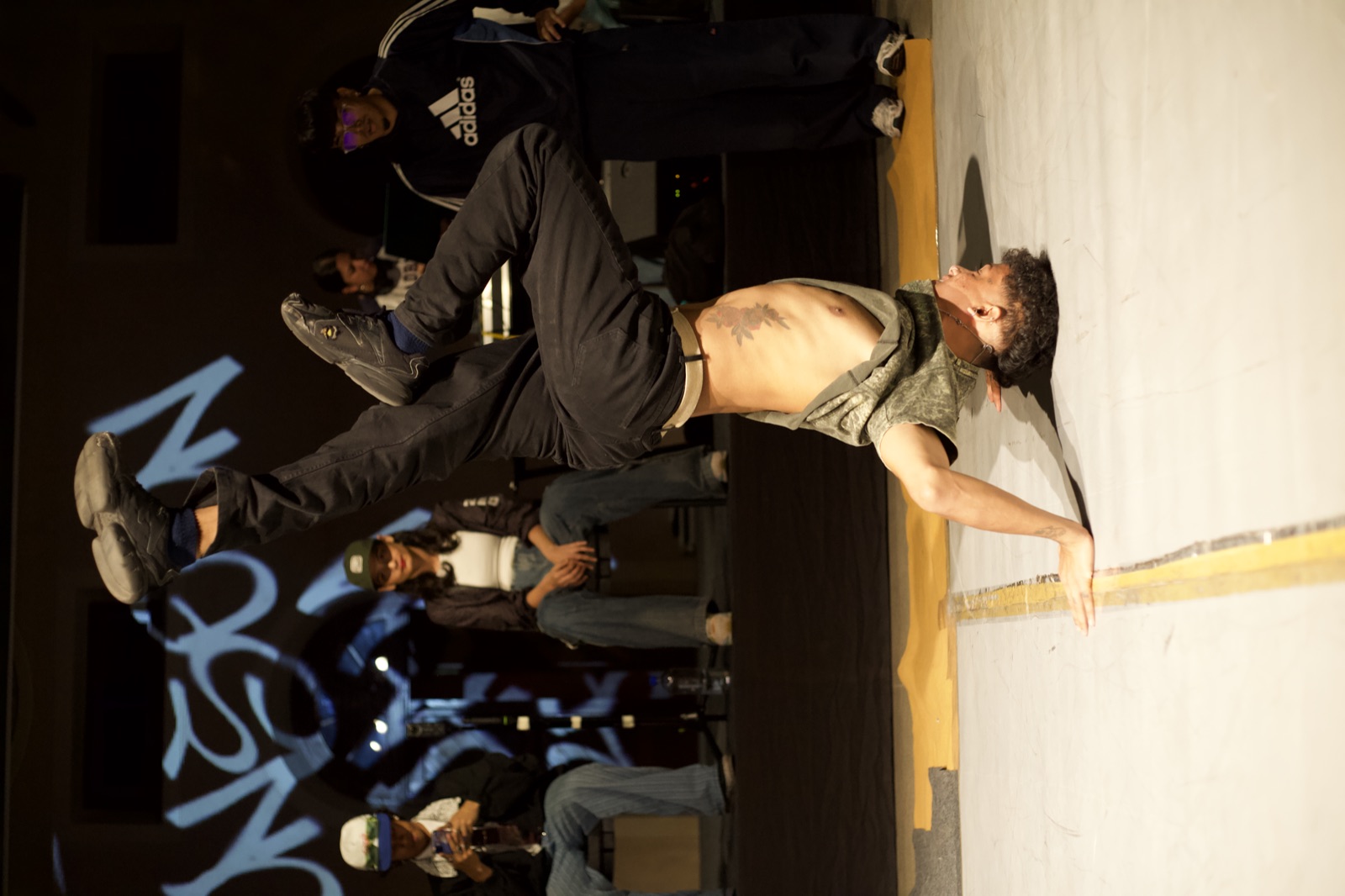 A b-boy inverted on his head mid-spin in front of the judges